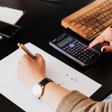 crop-woman-using-calculator-and-taking-notes-on-paper